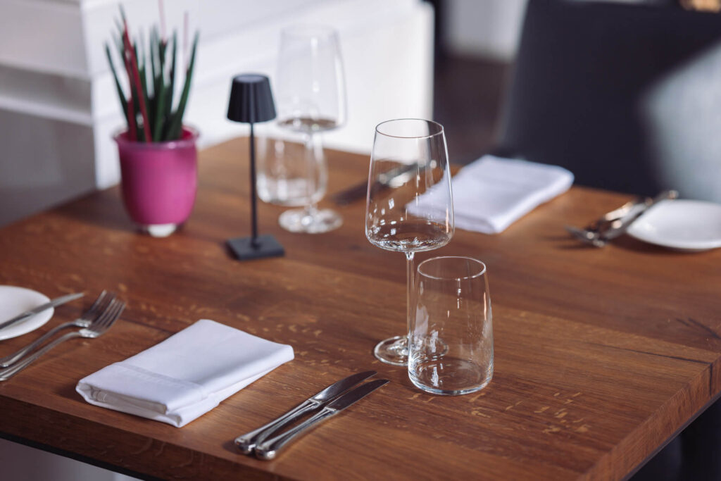 Gedeckter Holztisch mit Gläsern und Tischleuchte