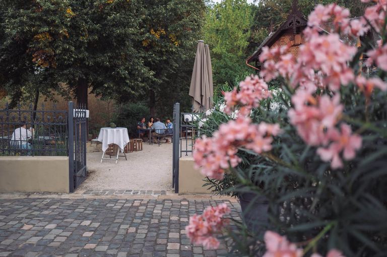 Eingang zum Garten Puricelli mit Blumen und Kopfsteinpflaster